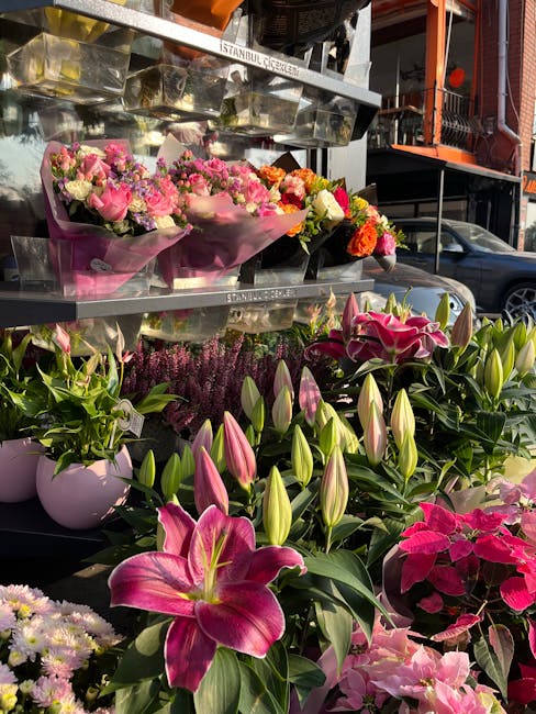 A display of fresh floral arrangements and individual potted flowers at a florist stall on Sidcup High Street. The arrangement includes bouquets wrapped in pink and purple paper, featuring pink roses,